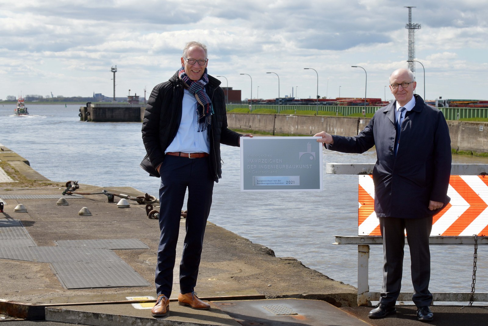 Der Präsident der Bundesingenieurkammer Dr. Heinrich Bökamp (rechts) und Torsten Sasse, Präsident der Ingenieurkammer Bremen mit der Ehrenplakette vor dem Wahrzeichen Nordschleuse in Bremerhaven. Foto: Michael Bahlo